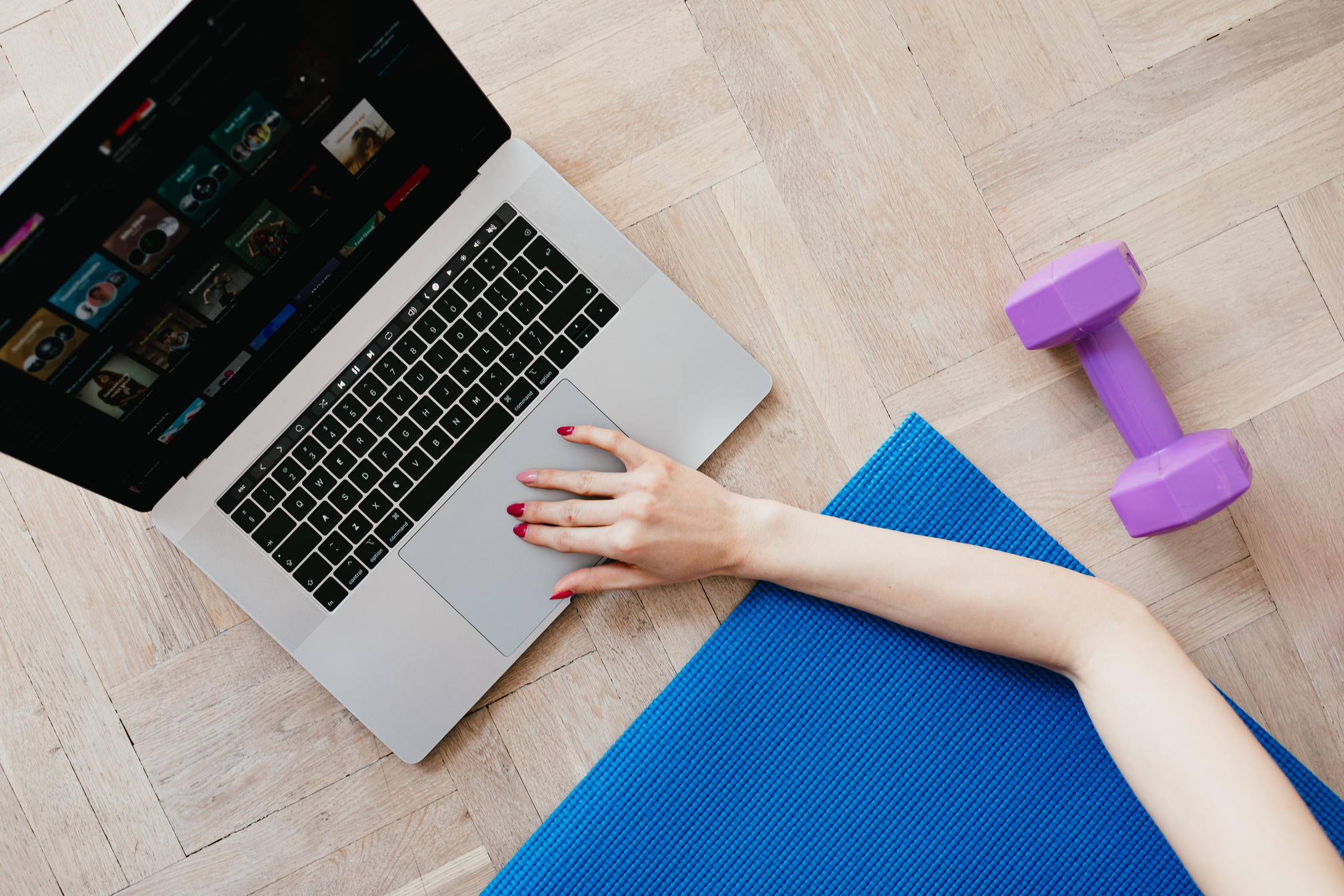 Crop woman with laptop and dumbbell on sports mat